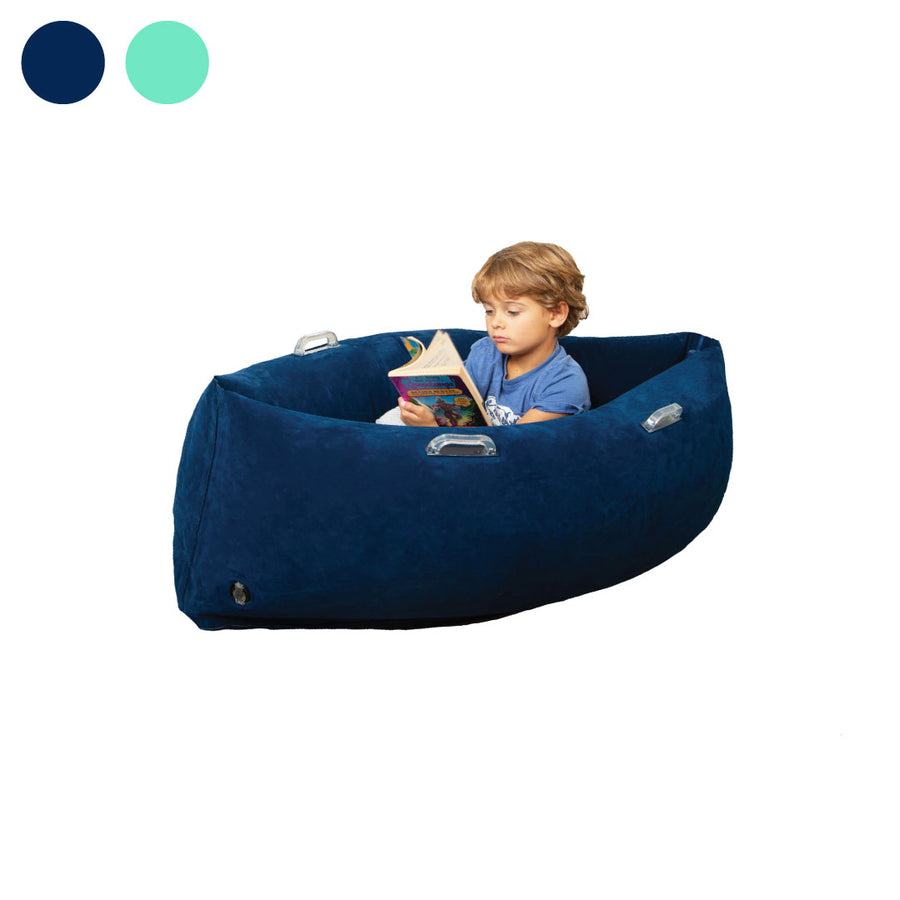 Young boy sitting in a dark blue inflatable sensory peapod while reading a book. Two color swatches (navy, teal) shown above.